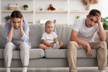 Aile içi çatışmalar. Evde tartıştıktan sonra gücenmiş ebeveynler arasında oturan tatlı bir bebek, çocuklu genç eşler, depresyonda ve hayal kırıklığına uğramış hissediyorlar, boş alan.