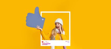 Heyecanını baş parmaklarıyla ifade eden genç bir kadın. Samimi sarı bir süveter ve parlak sarı bir arka planla çevrili kalın bir şapka giyer. Neşeli ifadesini arttırır..