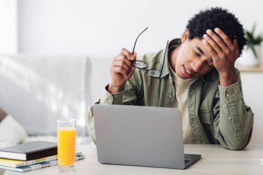 Evdeki bilgisayarın önünde online çalışmalar sırasında baş ağrısı çeken yorgun siyahi bir adam. Okul ödevlerini yapmaktan yorgun düşmüş Afrika kökenli Amerikalı ergen.