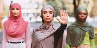 Dışarıda duran bir şeyi yasaklamayı ve protesto etmeyi bırakan üç Müslüman kadın. Kararlı İslami Kadın Grubu Cinsiyetçiliğe Hayır diyor. Panorama, Seçici Odaklanma