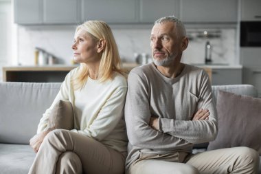 Üst düzey bir erkek ve kadın modern bir oturma odasındaki kanepenin iki ucunda oturur. İkisi de düşüncelere dalmış ve çözülmemiş sorunları üzerine kafa yorar. Duygusal mesafeyi vurgular..