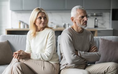 Üst düzey bir çift oturma odasındaki koltukta oturup anlaşmazlıklarını vurgularken duygusal olarak mesafeli görünüyor. Birbirlerine bakmaktan kaçınırken tansiyon gözle görülür..