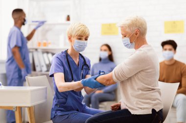 Covid-19 Aşı Kampanyası. Coronavirus aşısı olan yaşlı kadın hastanede doktorla otururken koluna enjekte edildi. Corona Virüs Nüfusu Bağışıklık Sistemi, Kapsamlı 19 Tedavi ve Tedavi