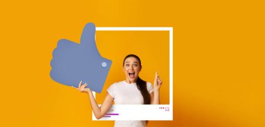 Genç bir kadın, parlak sarı bir arkaplan önünde poz verirken sevinçle onay veriyor. Sosyal medyada içeriği paylaşma konusunda hevesli görünüyor..