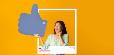 Genç bir kadın, canlı turuncu bir arka plana karşı büyük bir başparmak işareti ile sevinçle poz vererek, çevrimiçi içeriğine duyduğu heyecanı dile getiriyor. Şu anda takipçilerle olan bağlantısını vurguluyor..