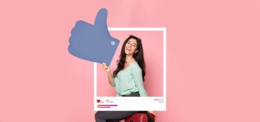 Genç bir kadın pembe bir arka plan önünde olumlu bir jestle sevinç ifade ediyor. Çevrimiçi etki ve bağlanma ruhunu somutlaştırıyor. Sosyal medya içeriği için mükemmel..