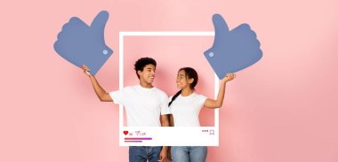 Genç bir erkek ve kadın gururla sosyal medya etkileşimini destekleyen büyük harflerle işaret ediyor..