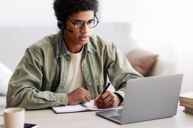 Çalışkan, kulaklık takmış, evden uzaktan ders çalışan, deftere yazı yazan zenci bir genç. Afro-Amerikalı öğrenci dizüstü bilgisayar dersi alıyor, video dersi izliyor, konferansa katılıyor.