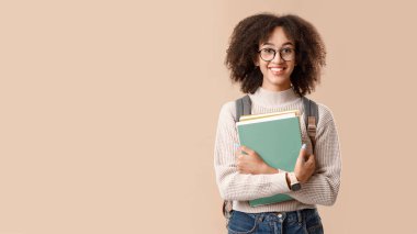 Kapatıldıktan sonra modern eğitim ve öğrenci ya da okula dönüş. Gözlüklü, sırt çantalı ve not defterli komik Afro-Amerikan kadın kameraya bakıyor, sarı arka planda izole edilmiş, stüdyo fotoğrafı.