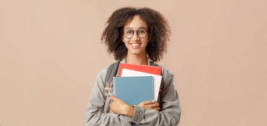 Okulda ya da üniversitede karantinadan sonraki dersler için hazırlık. Gözlüklü Afro-Amerikan bayan öğrencinin stüdyo fotoğrafı. Kameraya bakıyor, arka planda izole edilmiş, boş alan var.