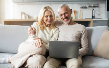 Son sınıf bir çift modern oturma odalarındaki rahat bir kanepede oturur, gülümser ve dizüstü bilgisayara bakarlar. Boş vakitlerinde sıcaklığa ve bağlantıya sarılı neşeli bir anı paylaşıyorlar..
