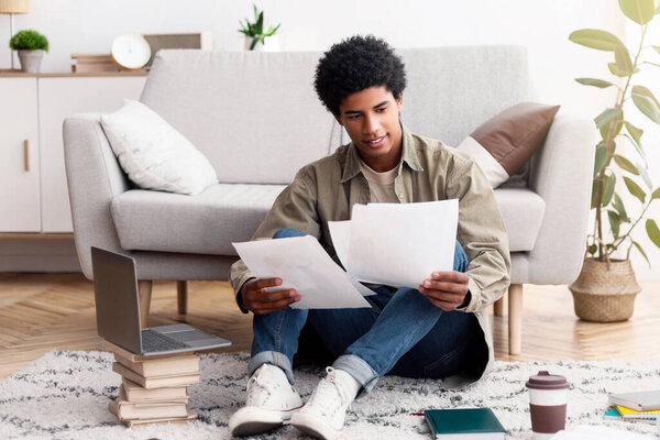 Полный портрет чернокожего студента-подростка, готовящего проект для своего онлайн-курса в университете дома. Афроамериканский подросток с бумагами, готовящимися к вебинару или удаленному экзамену