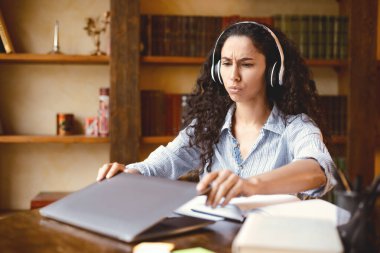 Tükenmiş insan. Çok çalışan genç bayan laptopu kapatıyor ya da açıyor, masada oturuyor. Yorgun kadın sanal online toplantıdan sonra yorgun. Bilgisayarı açıp kapatıyor, kablosuz kulaklık takıyor.