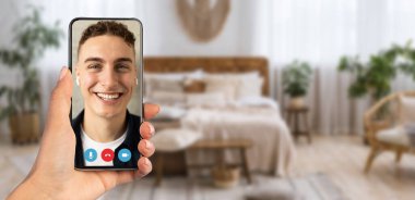 Bir insan rahat bir ev ortamında otururken akıllı bir telefonla canlı görüntülü sohbet etmekten zevk alır, telekomünikasyon ve sanal bağlantıların kolaylığını gösterir.