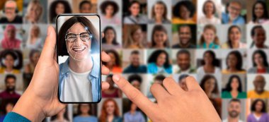 Bir el, gülümseyen bir yüzü analiz eden, yüz tanıma yazılımını gösteren bir akıllı telefonu tutuyor. Telefonun arkasında, çeşitli yüzlerden oluşan bir kolaj modern kimlik teknolojisini ve kullanımını vurguluyor.