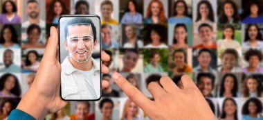 Bir kişi yüzünü akıllı telefonuyla tarıyor, çeşitli portreler kolajıyla çevrili..