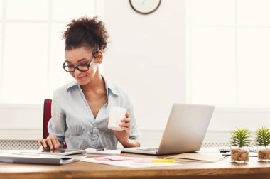 Kendine güvenen genç iş kadını ofiste, kopya alanı kahve oturma yudumlarken dijital tablet üzerinde çalışan resmi kıyafeti içinde