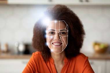 Modern yüz tanıma teknolojisi kimlik tespiti yaparken bir kadın gülümsüyor. Dekor, teknolojinin günlük yaşamla bütünleşmesini ön plana çıkaran iyi ışıklandırılmış bir mutfak..