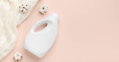 Sıvı deterjan şişesi ve beyaz yün kazak. Kumaş yumuşatıcı. Düzenli yıkama. Çamaşır konsepti. Pastel pembe arkaplan üzerinde metin veya logo için boş yer, panorama