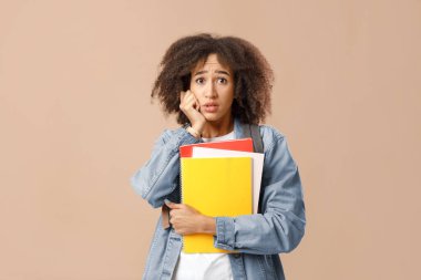 Ne yaptım ya da korku ve karmaşa, insani duygular. Şaşırmış ve üzgün, sırt çantalı Afro-Amerikan kadın elinde not defterleri ve baskılar, sarı arka planda izole edilmiş, stüdyo çekimi