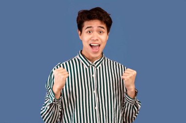 Vay canına, bu harika. Neşeli Asyalı bir adamın çığlığı ve sıkılmış yumrukları havada yükselirken mor stüdyo arka planında izole edilmiş. Olumlu gençler tezahürat yapıyor, zaferi kutluyor