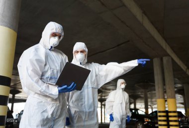 Özel virüs korumalı giysiler giyen adamlar halka açık otoparkta koronavirüs araştırması yapıyorlar, covid 2019, salgın hastalık