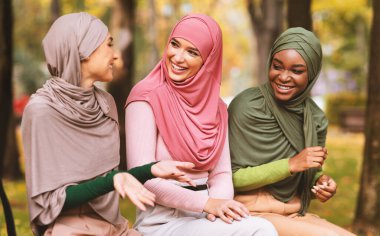 Hijab 'da üç Arap kadın şehir parkında bankta oturmuş sohbet etmekten keyif alıyorlar. Hafta sonu tatili, Müslüman Kadınlar Arkadaşlarla Buluşuyor. Kadın Arkadaşlığı Konsepti