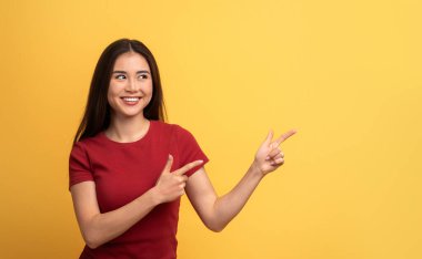 Uzun siyah saçlı genç bir kadın iki eliyle fotokopi alanına zıt yönleri işaret ederken neşeyle gülümsüyor. Parlak sarı arka plan onun enerjik davranışlarını arttırıyor..