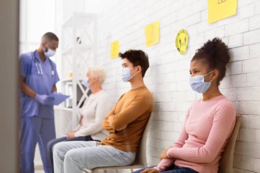 Coronavirus aşısı. Covid-19 aşısını bekleyen çeşitli hastalar hastane bekleme odasında kuyrukta bekliyor. Corona Virüs Önleme, Tıbbi Bağışıklık Kampanyası. Seçici Odaklanma