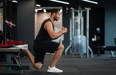 Portrait Of Athletic Black Man Making Bulgarian Split Squat Exercise At Gym, Motivated Young African American Male Training On Leg Muscles At Modern Sport Club, Enjoying Bodybuilding, Side View