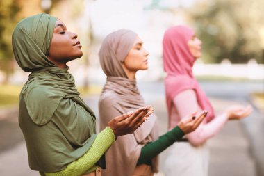 Türban ve modern giysiler takmış, dışarıda namaz kılan üç farklı İslamcı kadından oluşan bir grup. Müslüman Kadınlar Birlikte Dua Ediyor. İslam, Din Konsepti. Seçici Odaklanma