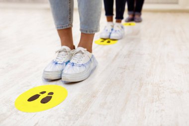 Sosyal Mesafe. Kuyrukta bekleyenler, ayakkabılar içinde ayakların kapatılması ve evin zemininde uyarı işaretleri. Covid-19, Coronavirus Önleme Arkaplanı. Kesilmiş, Metin İçin Boş Boşluk