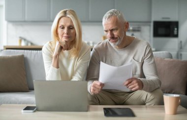 Üst düzey bir çift rahat bir oturma odasında kanepede oturur, önemli belgeleri dizüstü bilgisayarlarında incelerken endişeli bakarlar ve durumları hakkında derin tartışmalara girerler..