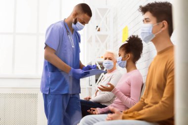 Coronavirus Covid-19 aşısı sırasında hastanede çok ırklı hastalarla konuşan Afrikalı erkek hemşire. Corona Virüsü için aşı, Kapsamlı Bağışıklık Kampanyası