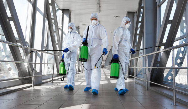 Биологическая опасность. Эпидемия коронавируса. Мужчины в защитном костюме и маске дезинфицируют туннель газом
.