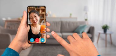 Bir kişi elinde eğlenceli bir video görüşmesi gösteren bir akıllı telefon tutuyor. Bir arkadaşlarıyla etkileşime girerler, sıcak bir oturma odasında içki içerler, modern iletişimi ön plana çıkarırlar..