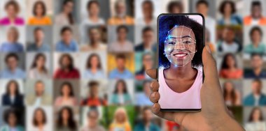 Bir akıllı telefon elinde tutulur, gülümseyen bir insanın yüz tanıma taramasını gösterir. Arka planda farklı yüzlerden oluşan bir kolaj var. Bu modern cihazlardaki gelişmiş teknolojiyi vurgular.