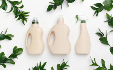 Sıvı deterjanlı plastik şişeler, doğal bitki özlü antibakteriyel jel ve beyaz arka planda yeşil yapraklar. Eko tarzı temizlik kavramı