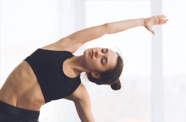 Fitness konsepti. Kollarını açıp evde yoga yapan rahat bir kız.