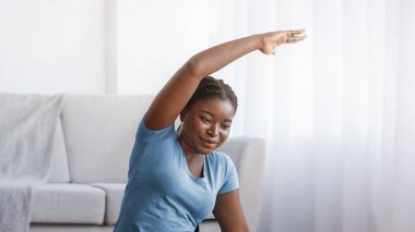 Çevrimiçi Fitness. Evde dizüstü bilgisayarın önünde gülümseyen siyahi kadın, spor Afrikalı Amerikalı kadın İnternet 'te özel ders izliyor, kas kaslarını esnetiyor ve ev içi egzersizlerin keyfini çıkarıyor, Boşluğu Kopyalıyor