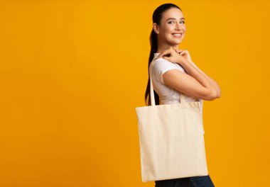 Plastiğe hayır de. Neşeli kız Sarı Stüdyo arka plan üzerinde boş beyaz eko çanta tutan. Boş Alan