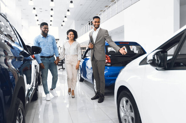 Продавец автомобилей показывает Роскошный автомобиль Консалтинг пара выбирая автомобиль в дилерском магазине. Покупка концепции транспортного средства