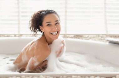 Köpükle kaplı sıcak köpük banyosunda oturan, evinde küvette dinlenen, özgür bir kadın. Çekici bin yıllık kadın içeride güzellik kaplıcalarının tadını çıkarıyor.