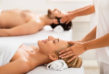 Yataklarda kapalı gözlerle uzanan, kafa masajı yapan çift. Sağlık, Akupres Terapisi ve Rahatlama Konsepti. Spa 'da güzellik günü. Seçici Odaklanma