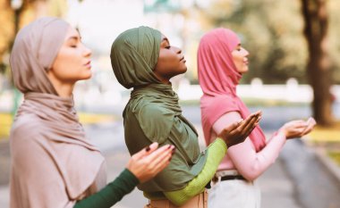 Geleneksel başörtüsü ve modern giysiler giyerek, Üç İslami Kadın Dışarıda Birlikte Dualar Ediyor. Müslüman Kadınlar Birlikte Dua Ediyor, Kadın Duası ve İslam Konsepti