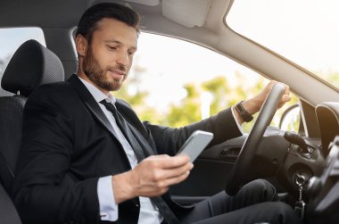 Yakışıklı bir iş adamı, cep telefonu kullanıyor, iş toplantısının konumunu, yan görüntüsünü, kopyalama alanını kontrol ediyor. Akıllı telefondaki GPS navigasyonunu kullanarak takım elbiseli girişimci.