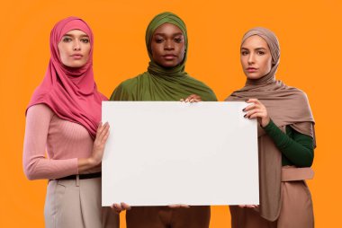 Sarı Stüdyo Arkaplanında Başörtüsü takan, Boş Kağıt Tutan Üç Ciddi Müslüman Kadın. Metin, Arap Kadın ve İnsan Hakları Konsepti için Sosyal Reklam. Model