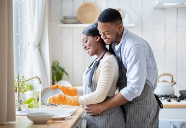 Kadın evde bulaşık yıkarken, siyah bir adamın karısını kucaklaması. Boş bir alan. Sevgili milenyum çifti ev işleri yapıyor, evi düzenliyor, temizlik yapıyor.