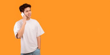 Her zaman temastayız. Akıllı telefonuyla konuşan sıradan gülümseyen Asyalı adamın portresi, fotokopi alanına bakıyor, turuncu stüdyo arka planında izole bir şekilde duruyor ve poz veriyor, afiş. İletişim, Telefon Çağrısı