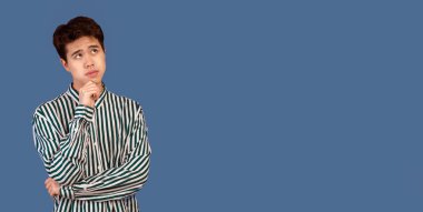 Fikir üzerinde kafa patlatıyorum. Fotokopi odasına bakan düşünceli Asyalı adamın portresi, çenesine dokunmak, Pastel stüdyo arka planında izole edilmiş. Düşünceli genç adam düşünüyor ve karar veriyor.